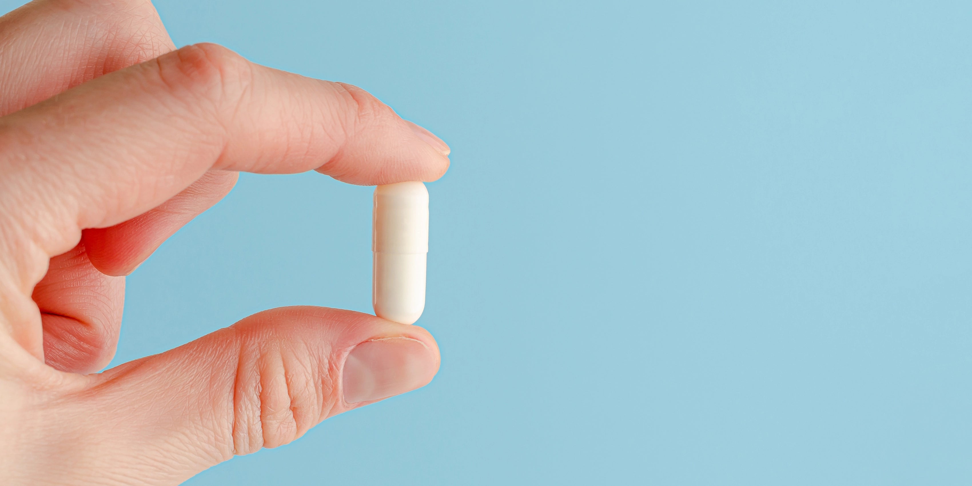 a capsule of b-complex next to a glass of water