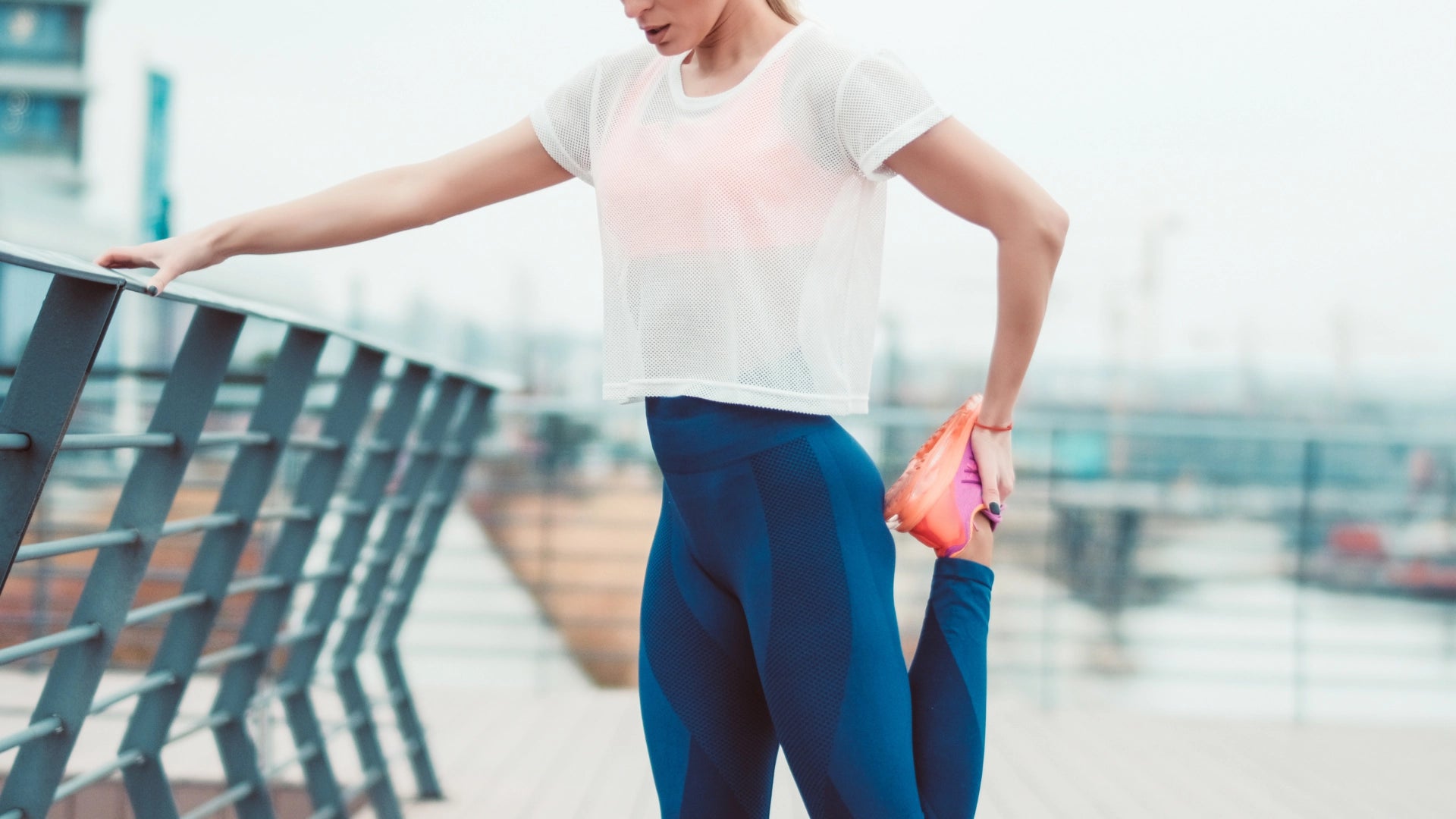 A woman standing at the park stretching her leg